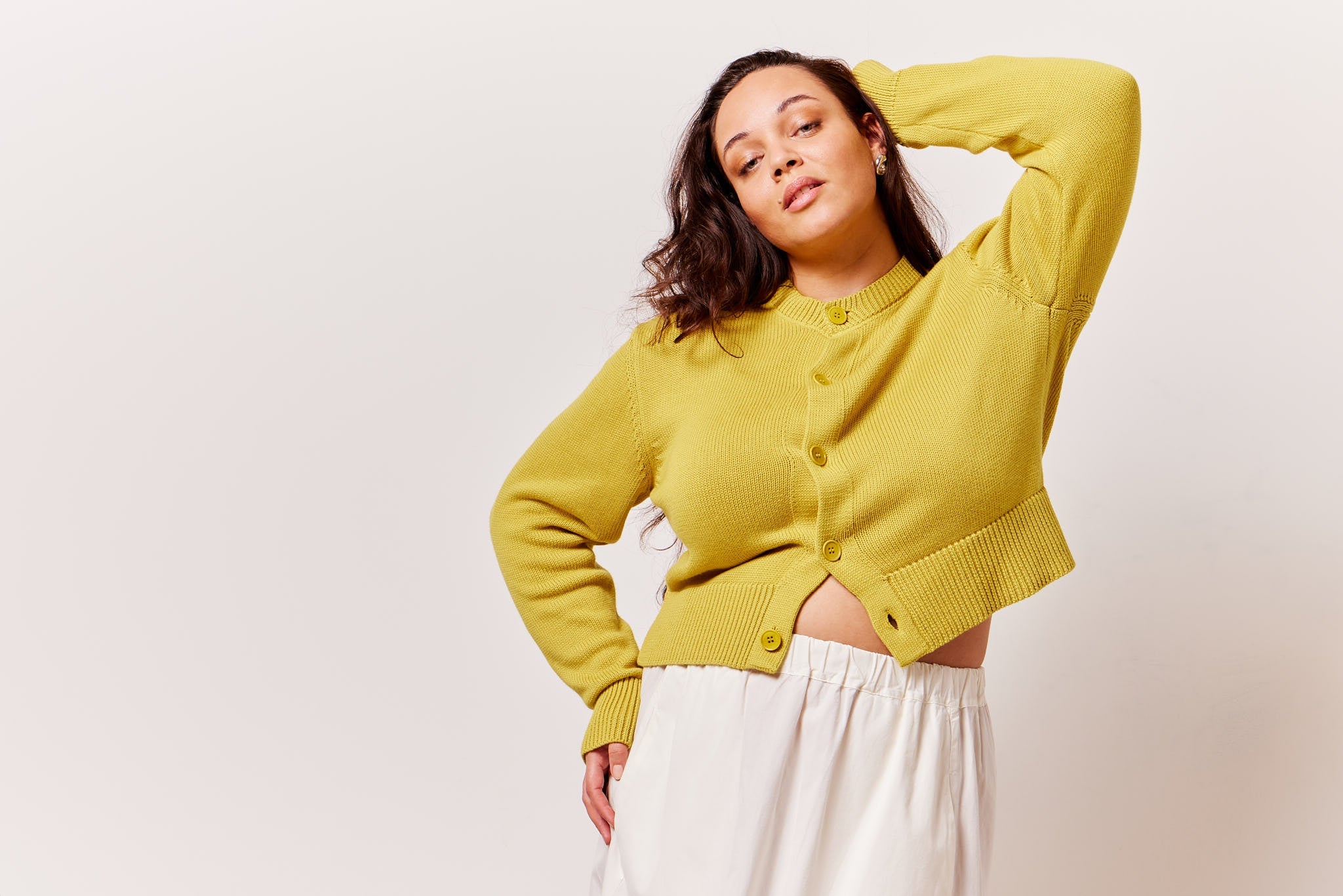 Woman wearing a yellow cardigan against a white background